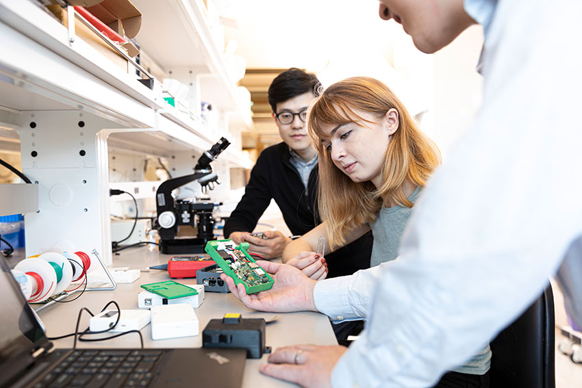 Students inspect the inner workings of an early device prototype