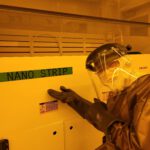 Jimmy covered in protective gear, posing in front of a machine in the clean lab.