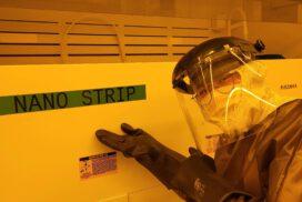 Jimmy covered in protective gear, posing in front of a machine in the clean lab.