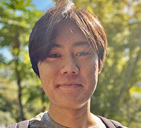 A headshot of Nick standing outside in front of trees.