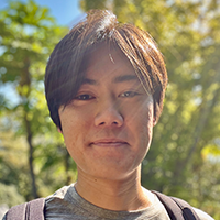 A headshot of Nick standing outside in front of trees.